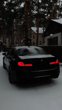 a black car parked in the snow next to a house