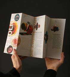 a person is holding an open book in their hands and it has pictures on the pages