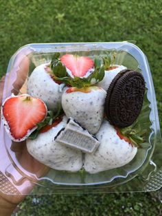 someone holding up a plastic container filled with cookies and strawberries