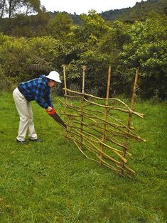 a man is bending over to pick up something from the grass