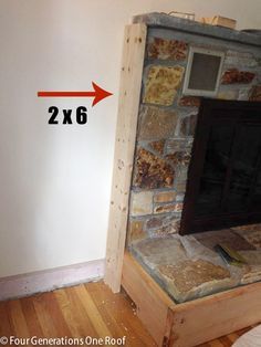 a living room with a stone fireplace next to a white wall and wood flooring