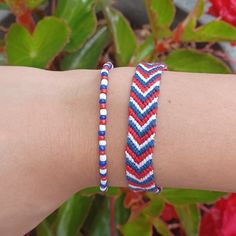 a woman's arm with two bracelets on it and flowers in the background