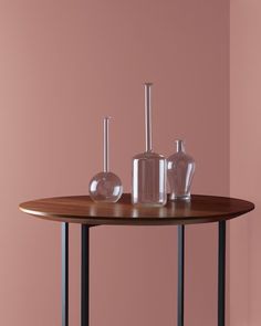 three vases on a table in front of a pink wall