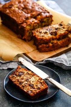 two slices of banana bread sitting on top of a black plate next to a knife