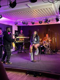 a woman sitting on top of a stool in front of microphones and music equipment