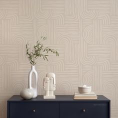 two vases and a plant sit on a dresser against a wallpapered background