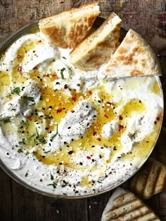 hummus and pita bread in a bowl on top of a wooden table,