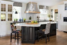 a large kitchen with an island in the middle and two stools at the end