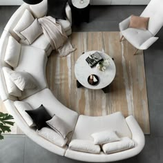 an overhead view of a living room with white couches and pillows on the floor