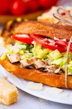 a close up of a sandwich on a plate with cheese and tomatoes in the background