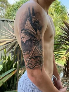 a man with a tattoo on his arm is standing in front of some plants and trees