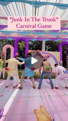 some people are dancing in front of a pink and purple sign that says junk in the trunk carnival game