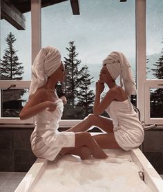 two women in robes sitting on a bath tub