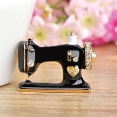 a black sewing machine sitting on top of a wooden table next to a white vase