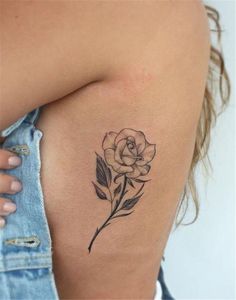 a woman's shoulder with a rose tattoo on it