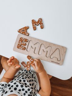 a baby laying on the floor playing with wooden letters