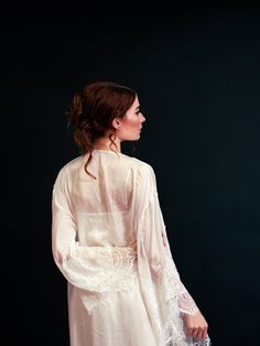 a woman in a white dress is standing with her back to the camera and looking off into the distance