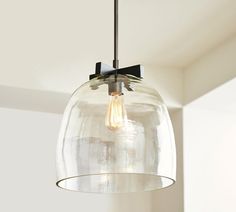 a clear glass light fixture hanging from a ceiling in a room with white walls and flooring