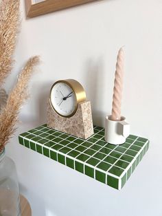 a clock and candle are on a shelf