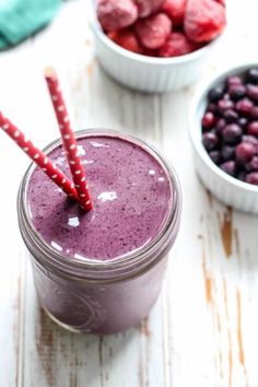 a smoothie in a mason jar with strawberries and blueberries next to it