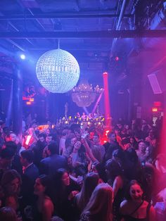 a large group of people in a room with lights and disco balls hanging from the ceiling