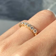 a woman's hand with a yellow gold wedding band and three diamonds on it