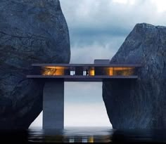 two people standing on a bridge over water with large rocks in the foreground and dark clouds above