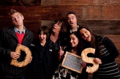 a group of people holding up wooden letters