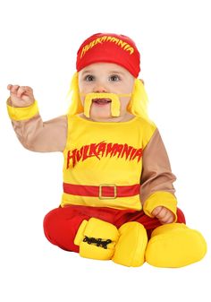 a baby dressed in a costume sitting on the floor with his mouth open and tongue out