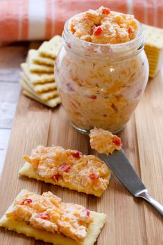 some crackers are on a cutting board next to a jar of food