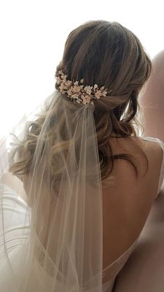 the back of a bride's head wearing a veil and hair comb with flowers on it