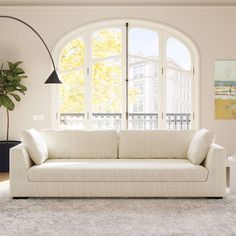 a white couch sitting in front of a large window