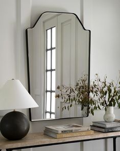 a mirror sitting on top of a table next to a lamp