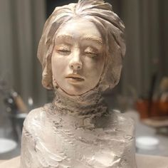 a sculpture of a woman's head with her eyes closed and hair pulled back