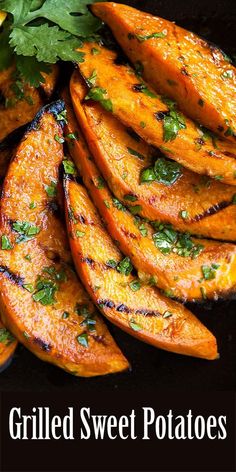 grilled sweet potato wedges with cilantro and parsley on a black plate