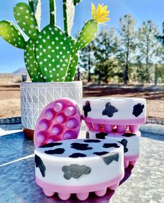 three soaps sitting on top of a table next to a cactus