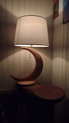 a lamp that is sitting on top of a table next to a night stand with a wooden base