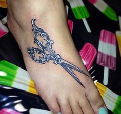 a woman's foot with a tattoo on it and a pair of scissors in the middle