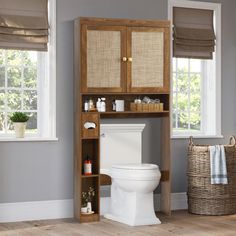 a toilet sitting next to a wooden cabinet in a bathroom