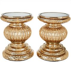 two gold colored candlesticks sitting next to each other