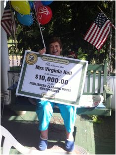 a man sitting on a bench holding up a large check for $ 10, 000