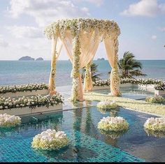 an outdoor wedding setup with white flowers and greenery on the water's edge