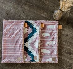 three blankets with animals on them sitting on top of a wooden floor next to a vase