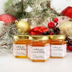 three jars of honey sitting next to christmas decorations