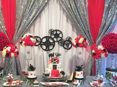 a table topped with red and white flowers next to silver sequins covered walls