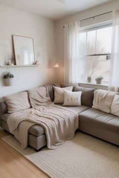 a living room with a couch, window and rugs on the hardwood flooring