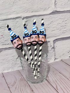 four paper straws in the shape of three men's heads with blue and white striped hats