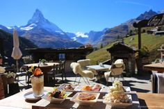 an outdoor dining area with mountains in the background and food on trays sitting on a table