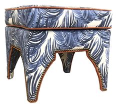 an upholstered stool with blue and white leaves on the top, sitting against a white background