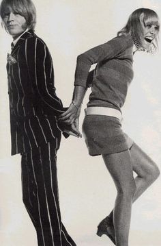 two people dressed in clothing posing for the camera with their hands on each other's hips